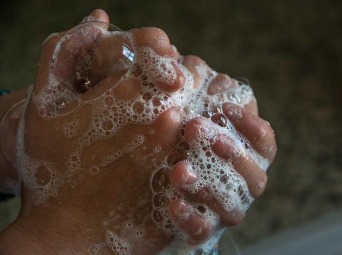Pair of hands grasped together covered in white soapy bubbles